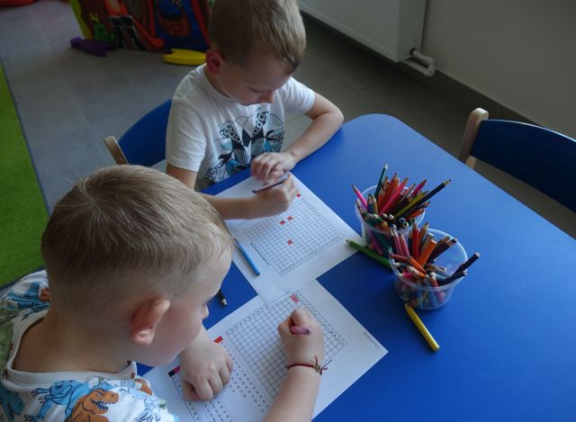 chłopiec i dziewczynka rozkodowują obrazki siedząc przy stoliku