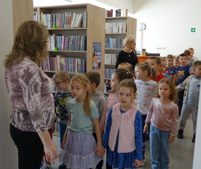 przedszkolaki spacerują pomiędzy regałami z książkami