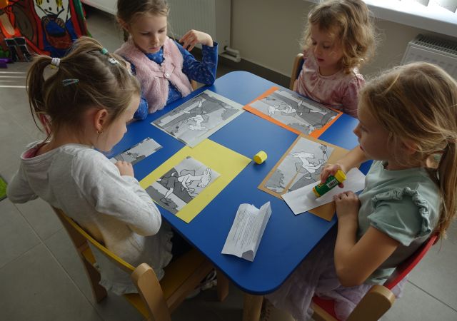 dzieci naklejają puzle z wyciętych bajek na kartki