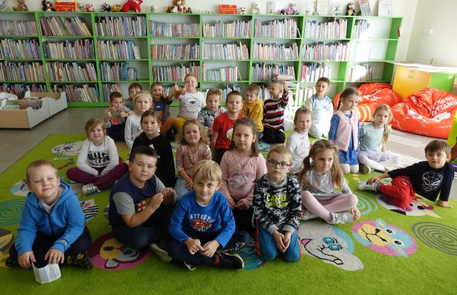 przedszkolaki pozują do zdjęcia, w tle regały z książkami
