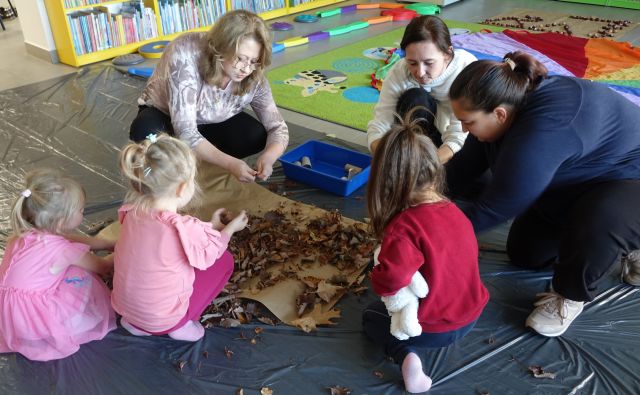 dzieci i osoby dorosłę mieszają w suchych liściach