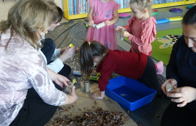 dzieci i dorosłe kobiety mieszają w kasztach i liściach