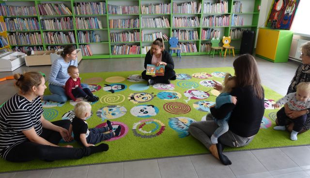 biblkiotekarka czyta dzieciom i opiekunom książkę
