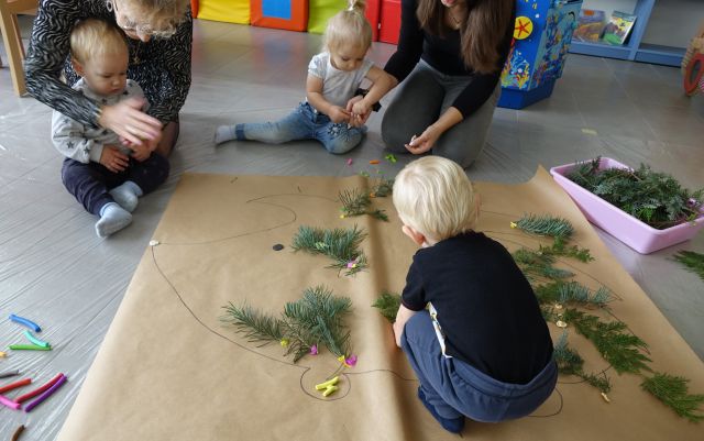 dzieci z mamami układają gałązki świerku