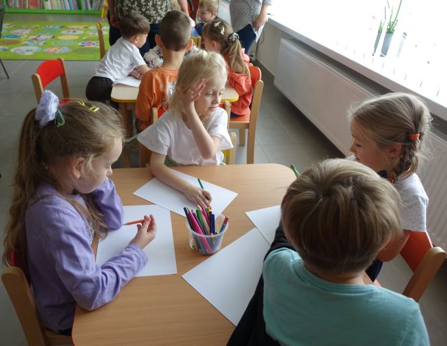 dzieci siedzą przy stoliku i rysują