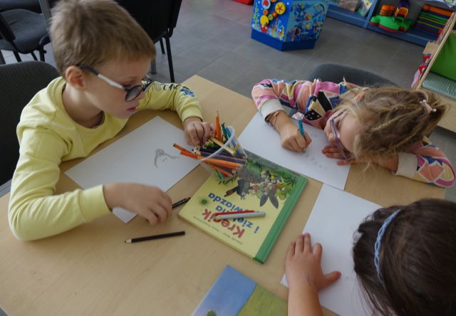 dzieci siedzą przy stoliku i rysują