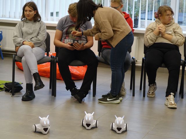 młodzież steruje robotami Photon siedząc na krzesłach