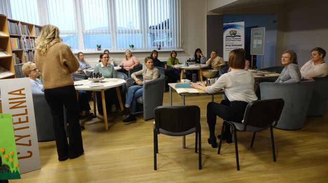 kobiety uczestniczące w warsztatach siedzą na siwych fotelach przy okrągłych stołach