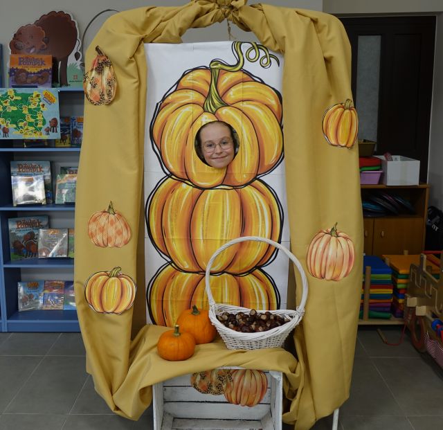 dziewczynka pozuje do zdjęcia w fotobudce z dyni