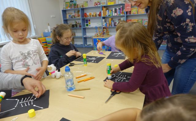 dzieci wykonują pozstaci z patyczków na czarnej kartce