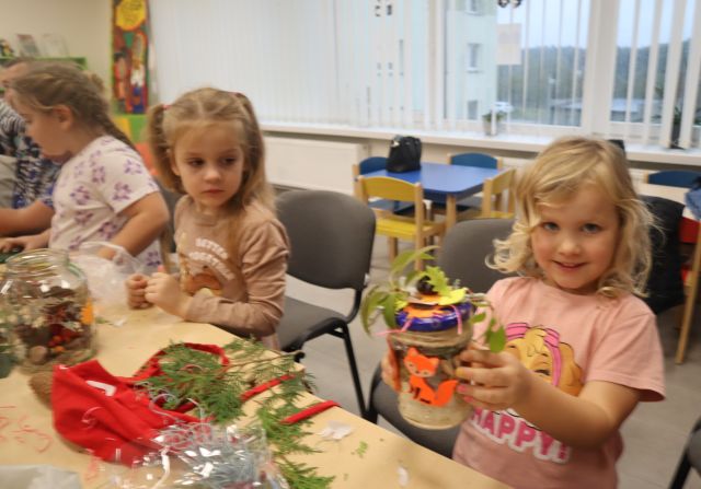 dziewczynka pokazuje wykonany przez siebie słoik z darami jesieni