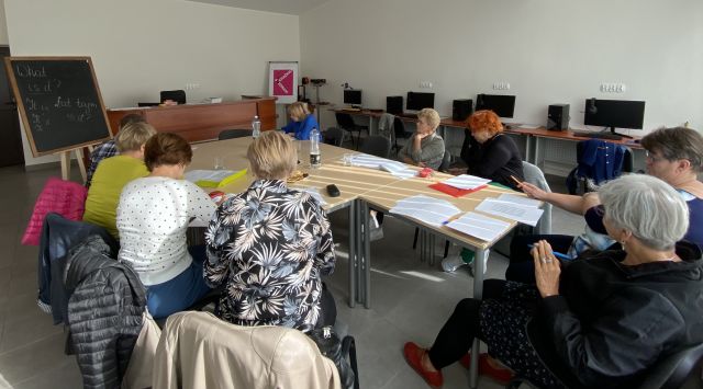 seniorzy siedzą przy stolikach, na których mają kartki