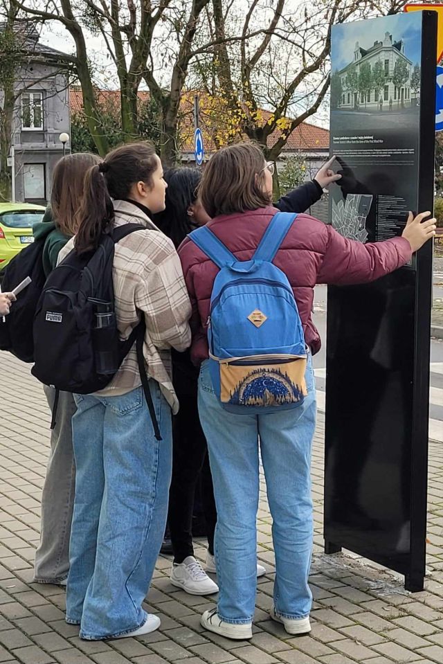 młodzież czytająca informacje na planszy w przestrzeni miejskiej