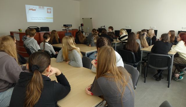 młodzież siedzi w sali komputerowej przy stołach i ogląda film