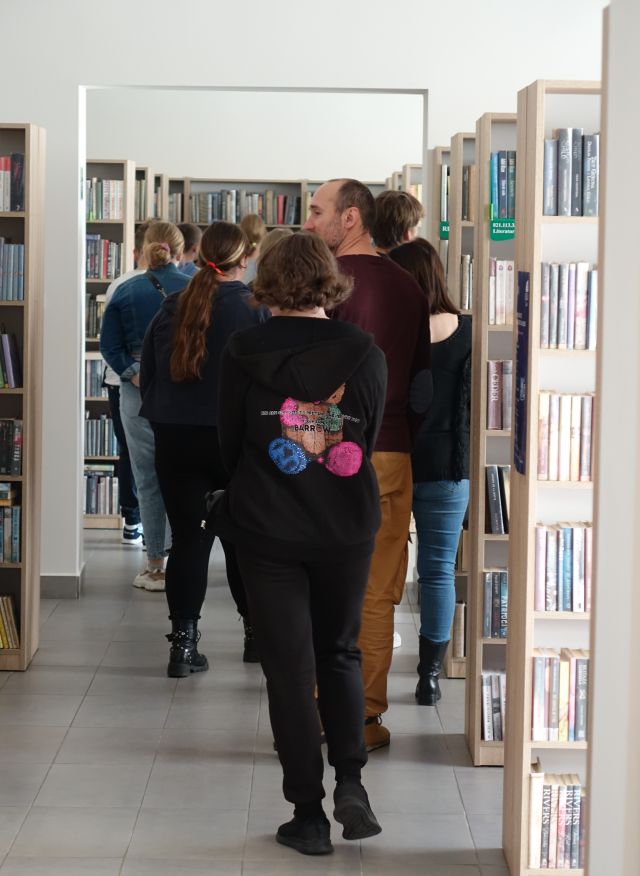 młodzież spaceruje pomiędzy regałami z książkami