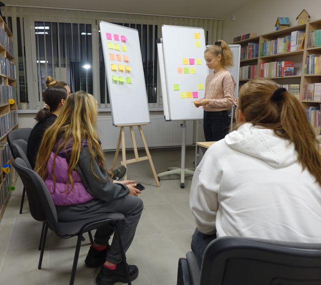 dziewczyna stoi przed flipchartem z kolorowymi karteczkami