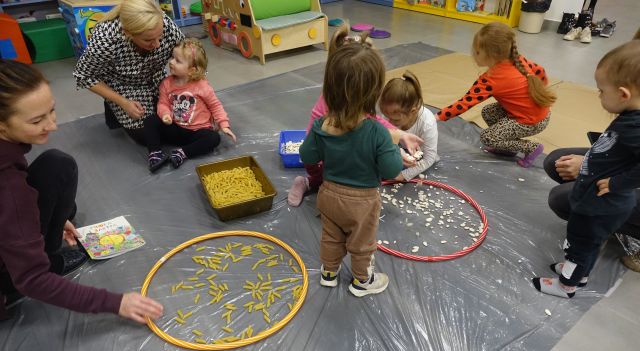 dzieci bawią się usypując zegar z ziaren w kole