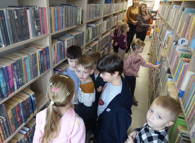 przedszkolaki spacerują pomiędzy regałami z ksiązkami