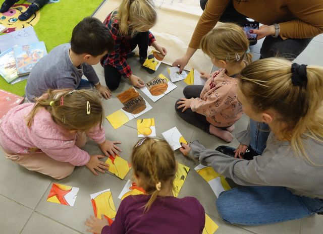 przedszkolaki ukłądają na podłodze puzle Kubusia Puchatka