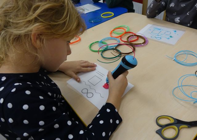 dziewczynka drukuje długopisem 3D figury geometryczne