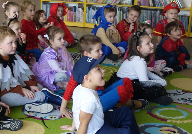 prezdszkolaki przebrane za postacie z bajek siedzą na kolorowym dywanie