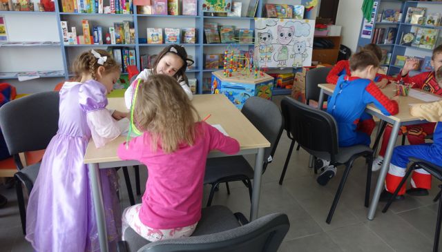 przedszkalaki siedzące przy stolikach rysują na kartkach