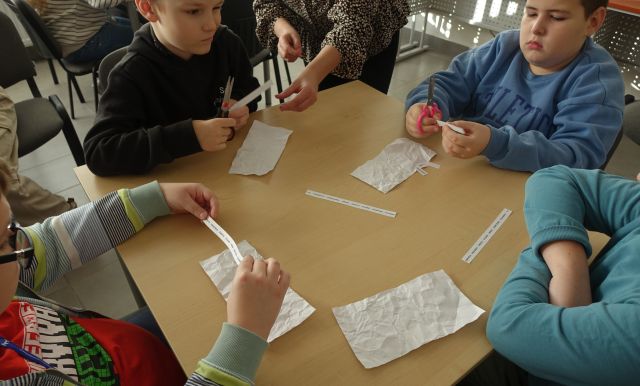 uczniowie czytają teksty na cienkich kartkach