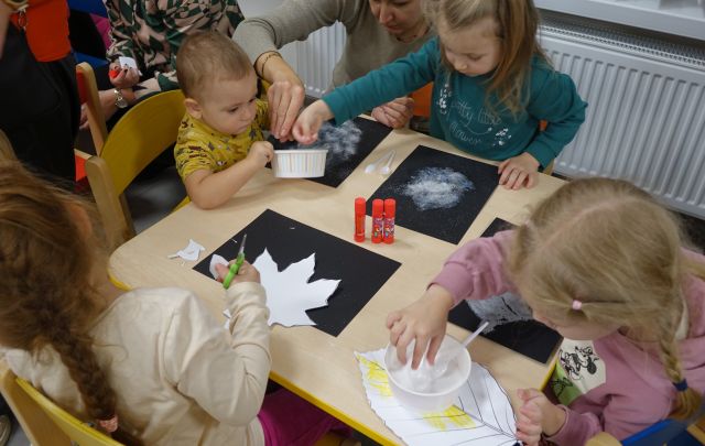 dzieci odrysowują liście na czarnych kartkach