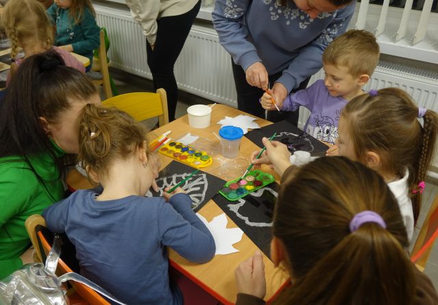 dzieci malują białe liście na czarnych kartkach