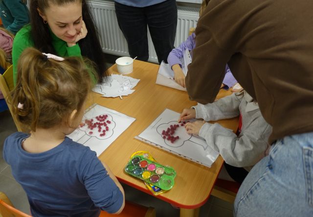 dzieci i rodzice wyklejają drzewa kulkami z bibluły