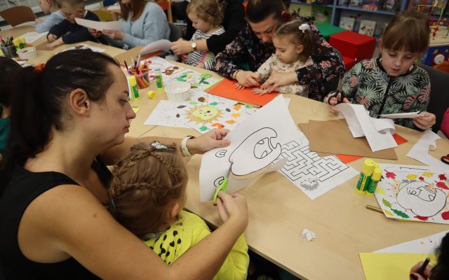 dzieci i opiekunowie wycinają z kartek