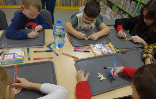 chłopcy kolorują drewniane breloczki