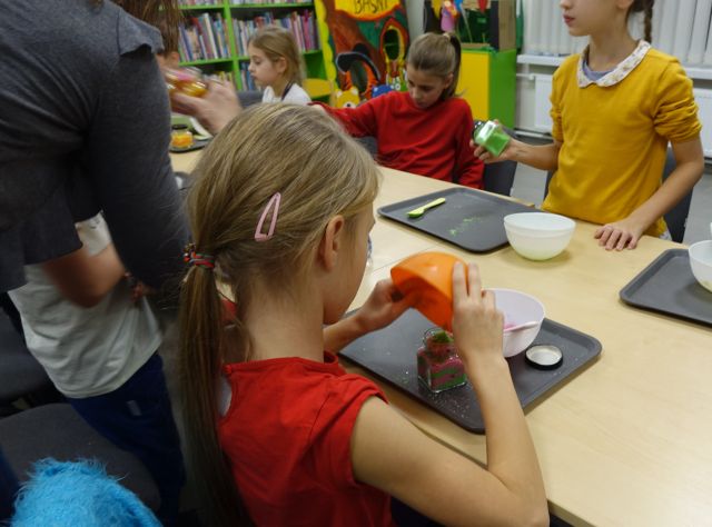 dziewczynka przesypuje kolorową sól do kąpieli do słoiczka