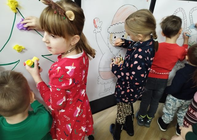 dzieci kolorują dużego Mikołąja