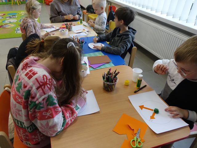 dzieci siedzą przy stołach i malują