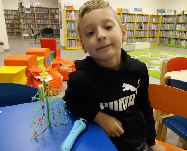 chłopiec prezentuje wykonaną przez siebie długopisem 3D choinkę