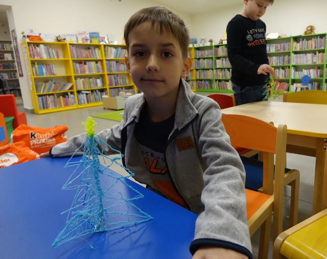 chłopiec prezentuje wykonaną przez siebie długopisem 3D choinkę