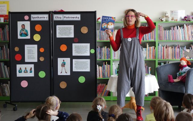 atorka stojąca przed dziećmi pokazuje książkę