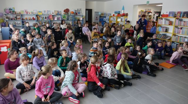 sala biblioteczna wypełniona dziećmi uczestniczącymi w spotkaniu autorskim