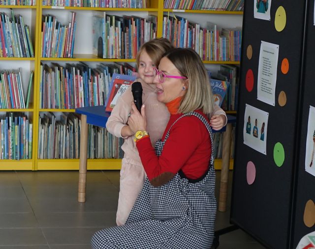 autorka książek z dziewczynką, w tle regały z książkami