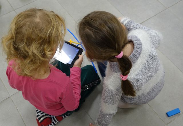 dwie dziewczynki spoglądają w tablet