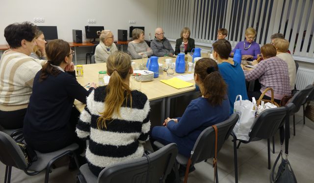 15 osób uczestniczących w spotkaniu siedzi przy stołach