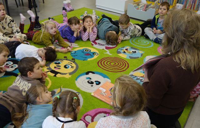przedszkolaki leżą na kolorowym dywanie