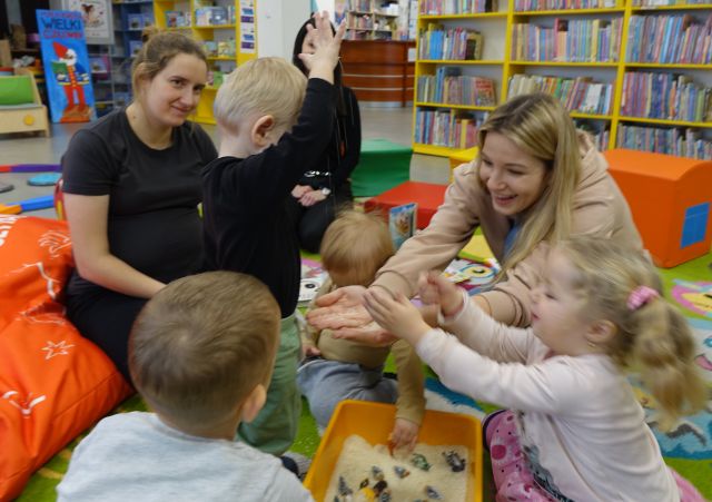 mamusie i małę dzieci bawią się ryżem wsypanym do miski i ukrytymi w nim zwierzątkami