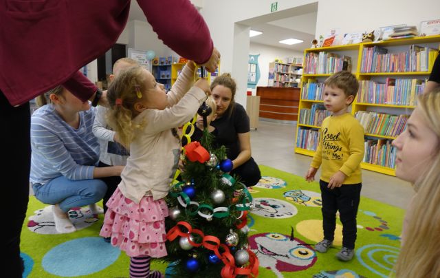 dzieci z mamusiami ubierają choinkę wykonanym przez siebie łańcuchem