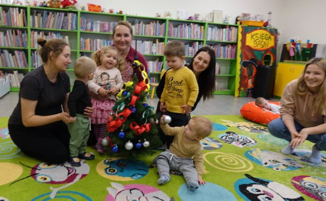 małę dzieci i mamusie pozują do zdjęcia z ubraną przez siebie małą choinką