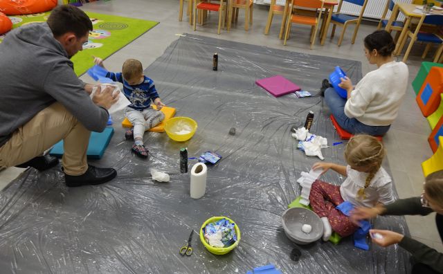 dzieci siedzące na podłodze robią śnieg