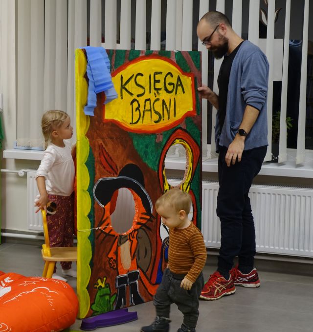 dziewczynka i chłopiec z tatusiem stoją przy fotobudce Świat baśni
