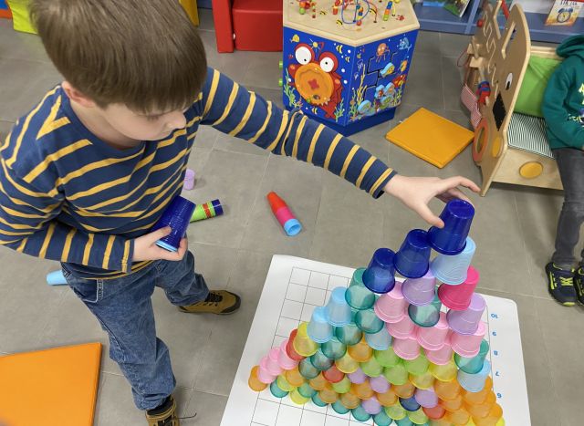 chłopiec układa wieżę z kolorowych kubeczków