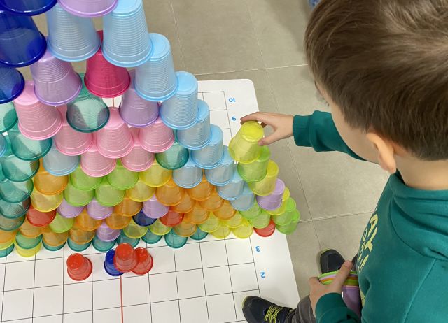 chłopiec ukłąda wieżę z kolorowych kubeczków